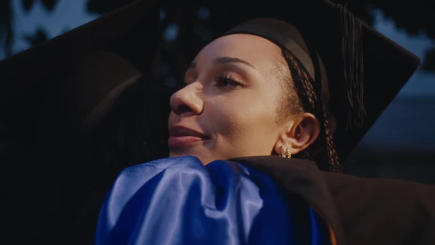 Two female graduates in gowns hugging each other
