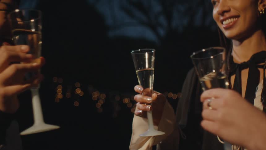 Three women clink glasses of champagne as a flash goes off