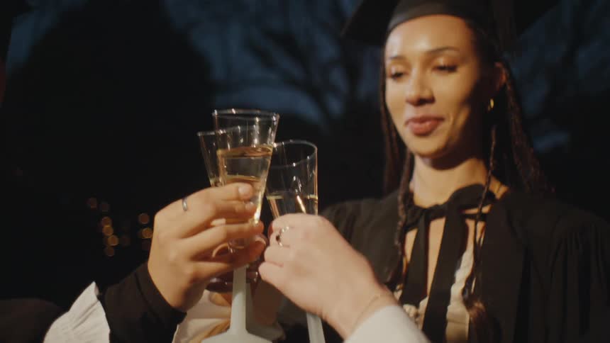 Three people toast with champagne flutes dressed in formal attire against a dark background suggesting nighttime