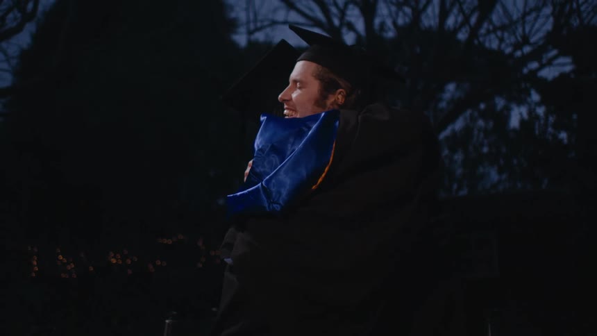 Two male graduating students hug each other outdoors