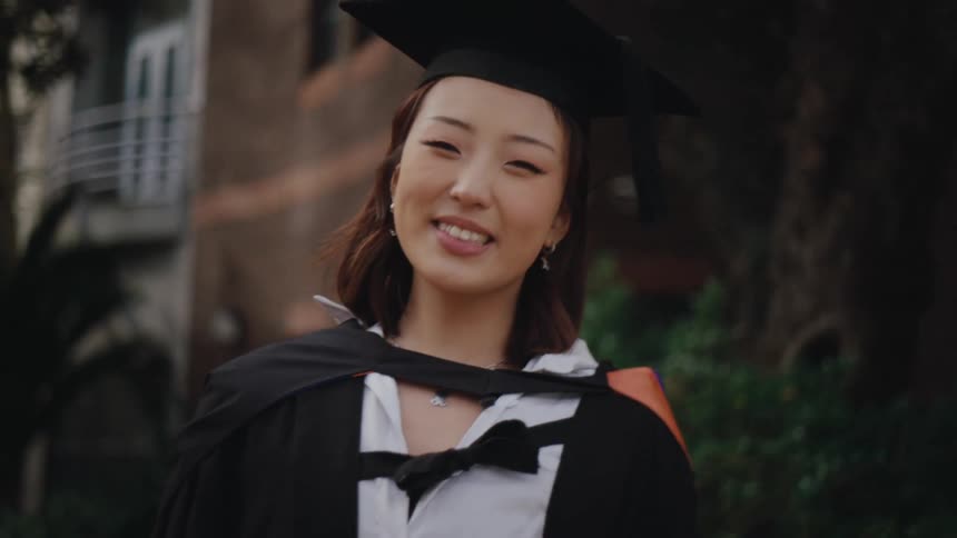 Cheerful woman while wearing graduation gown