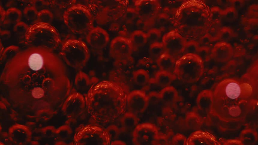 Extreme close up of a red carbonated liquid with bubbles