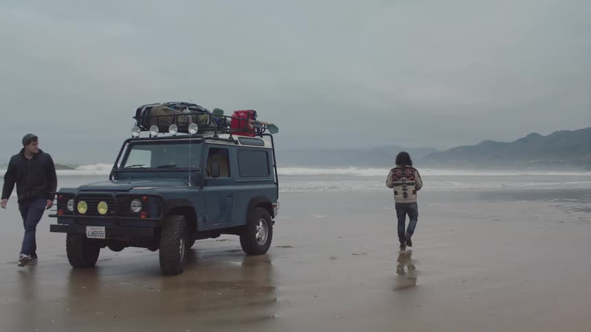 People get out of a vehicle parked on the beach on a cloudy day