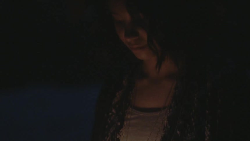 Woman looking at a candle in the darkness