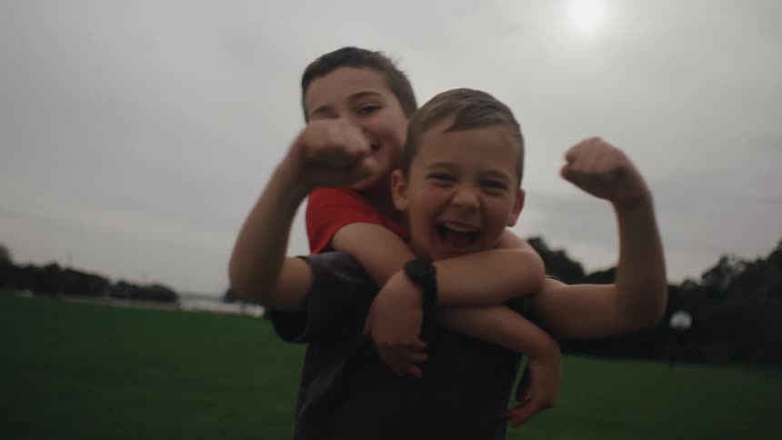 Two boys with their arms up vibrant and happy