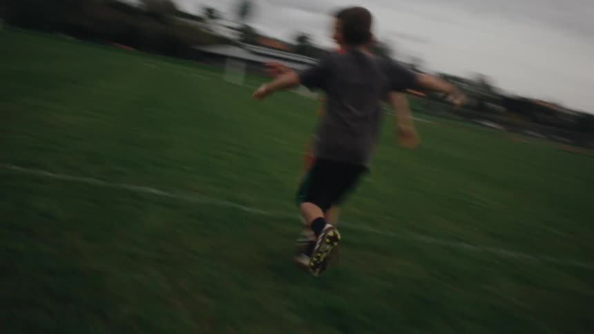 A couple of boys running around and roughhousing on a soccer field