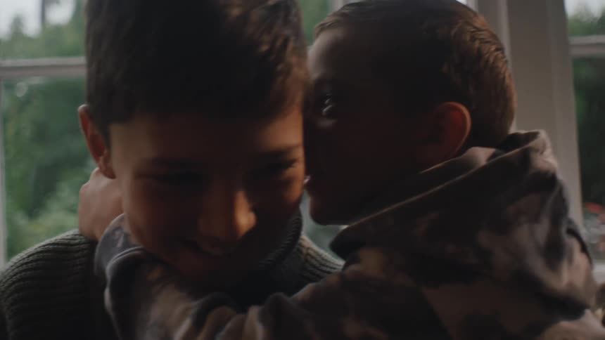 Little boy whispering in another boys ear