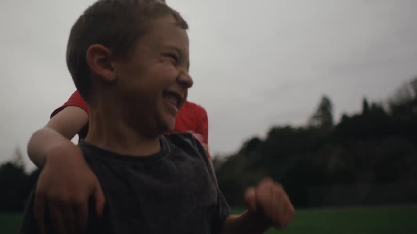 Two boys in a grass field jumping and cheering with joy