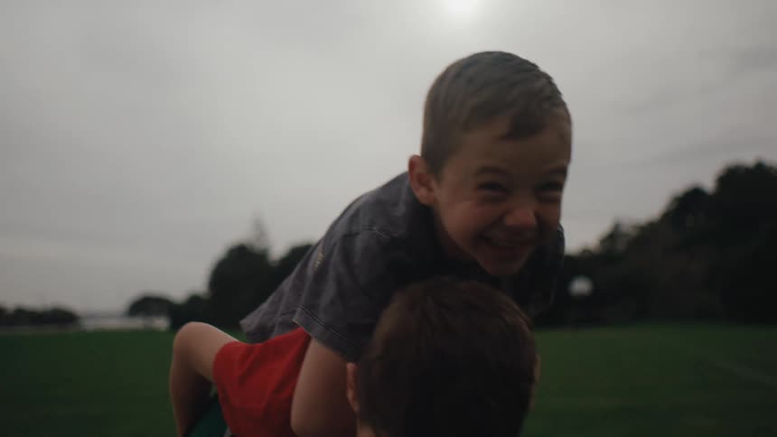 Two children on a soccer field one giving the other a piggyback ride