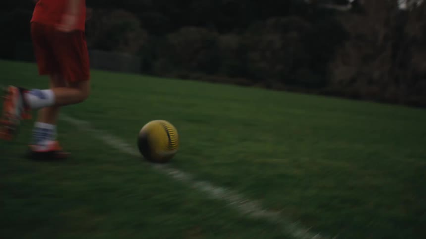 Boy running with the ball on a soccer field and missing the shot towards the goal