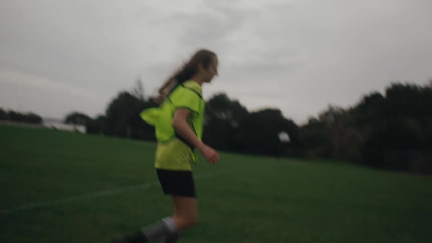 Girl playing soccer and kicking the ball towards the goal