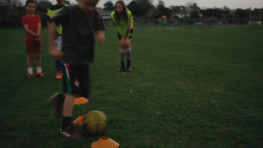 Small group of children practice soccer drills on a field