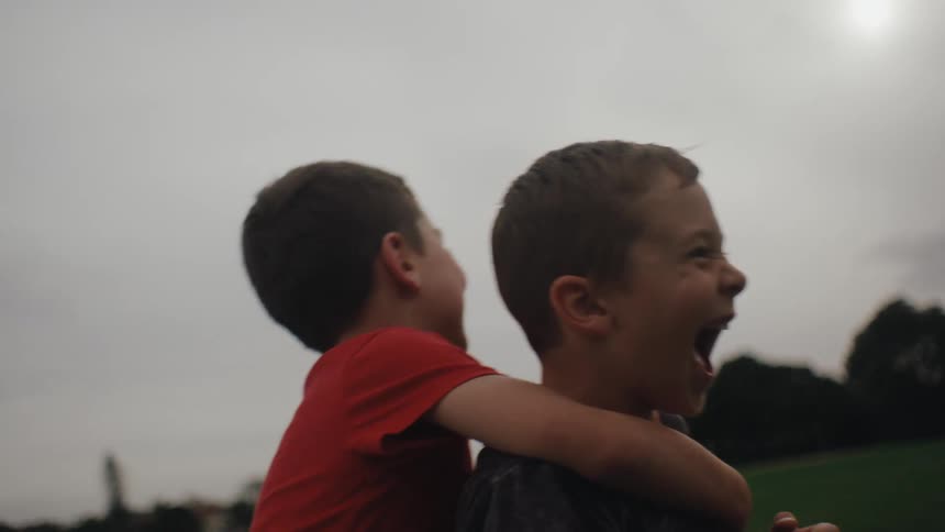 Two boys hug each other to celebrate a goal on a soccer field