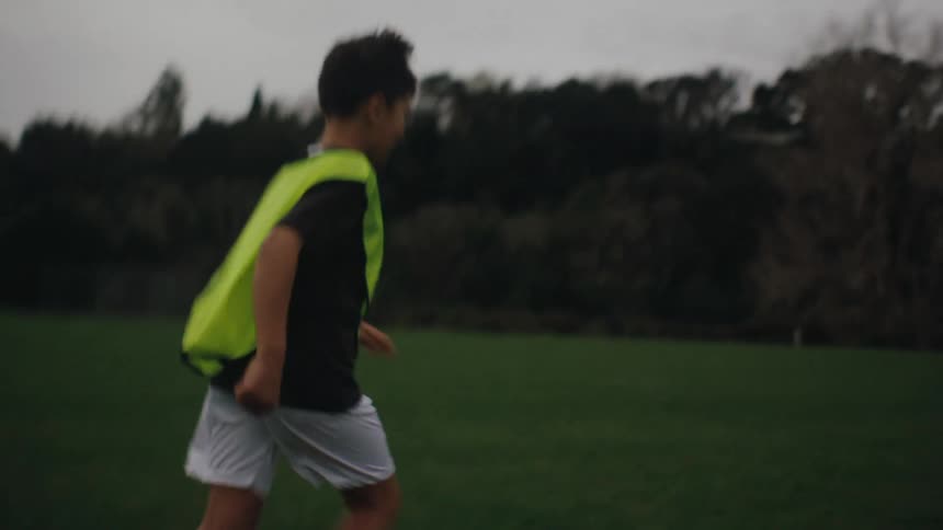 Boy running with a ball playing soccer and kicking it towards the other boy who was in the goal