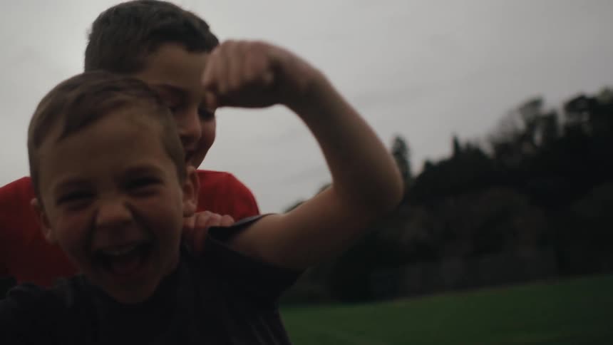 A child runs up and wrestles with his friend