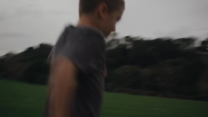 Two boys play soccer on a green field
