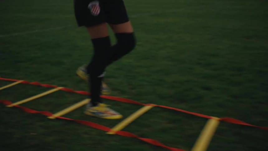 Girl jumping and running in an educational warmup on a grassy field
