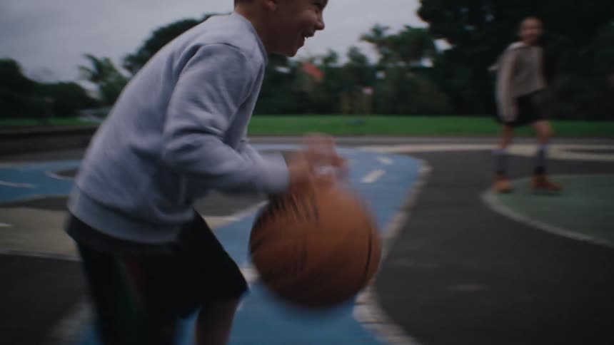 Children on a court on a cloudy day playing basketball