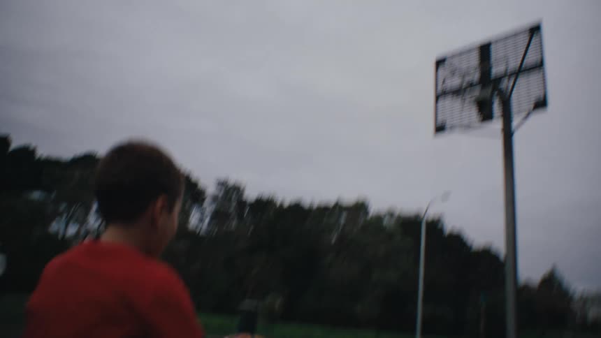 Boys playing basketball on a court on a cloudy day