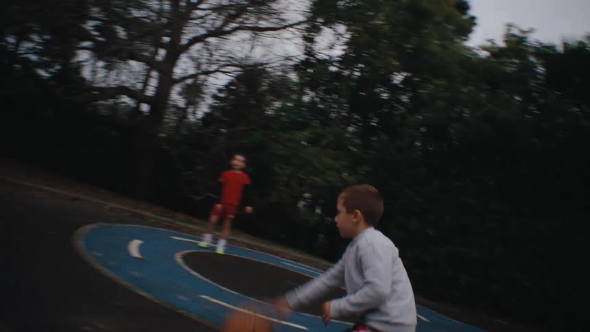 A boy dribbles a basketball on an outdoor court