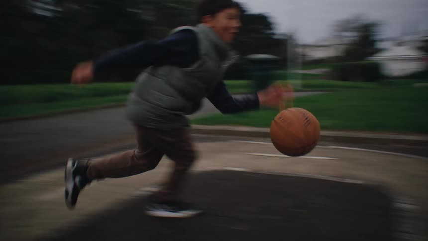 Children play basketball on an outdoor court in a park