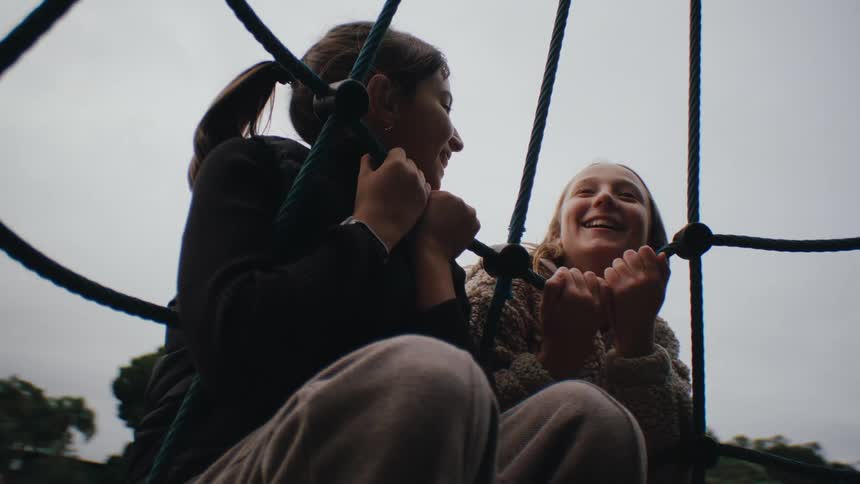 Two girls holding on with their hands to the strings of a spinning toy