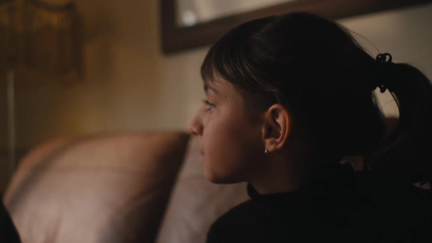 Girl sitting in the living room at home smiles while listening to another person