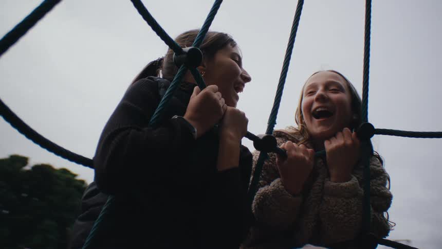 Portrait of two girls holding on to a rope on a spinning toy