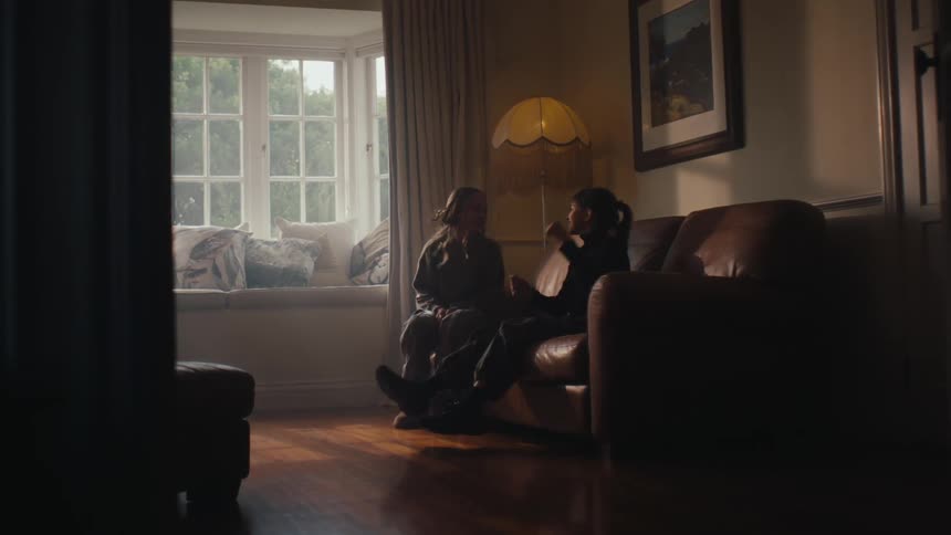 Little girl sitting with friend on the couch in the living room and talking to each other