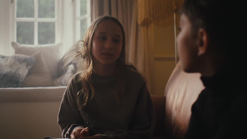 Two girls talk with each other in the living room