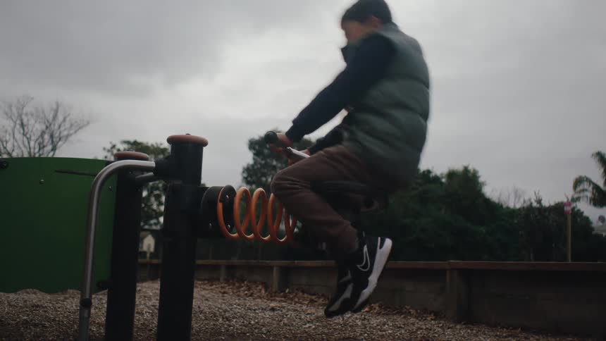 A boy rides a springmounted playground toy bobbing up and down