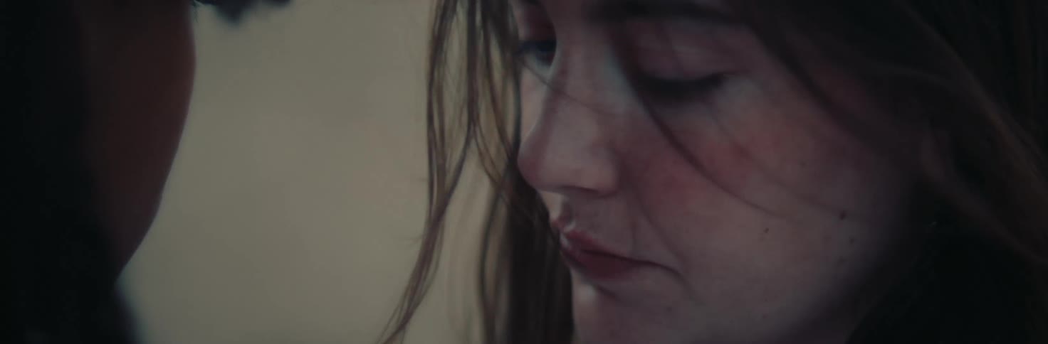 Wind blows through a womans hair as she glances up and then back down again