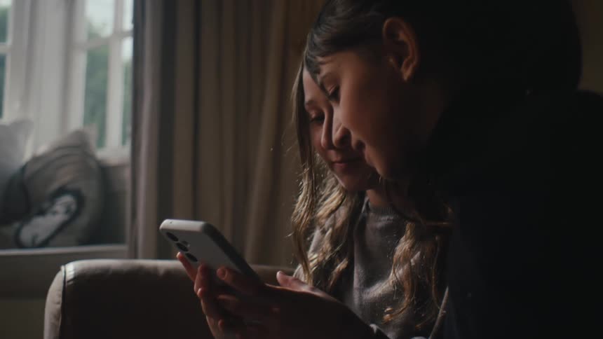 Two little girls sitting using their smartphones