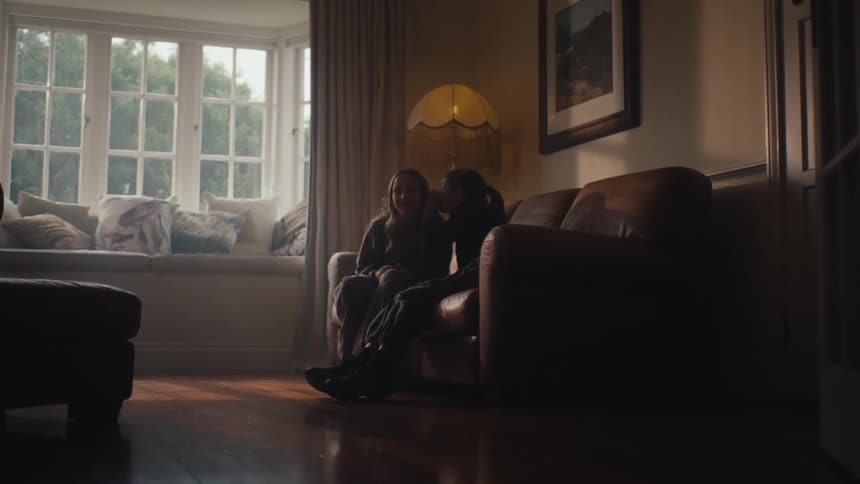 Two girls hugging each other and sitting on the couch in the living room and talking to each other