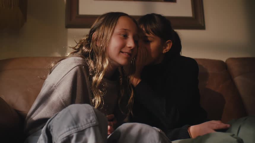 Two girls whispering in each others ears