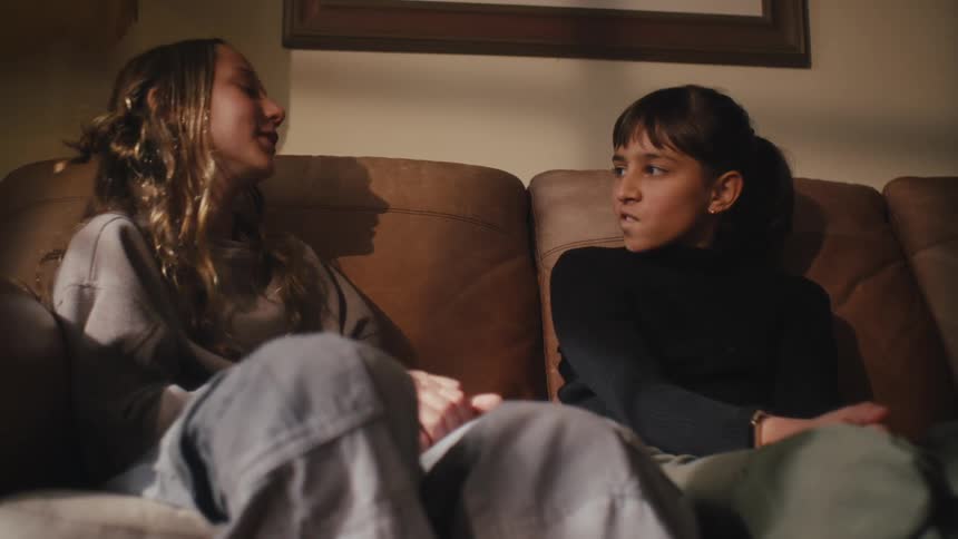 Two girls sitting on the couch talking to each other