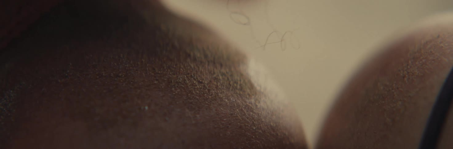 A close up of the skin of the shoulder of a person with curly hair
