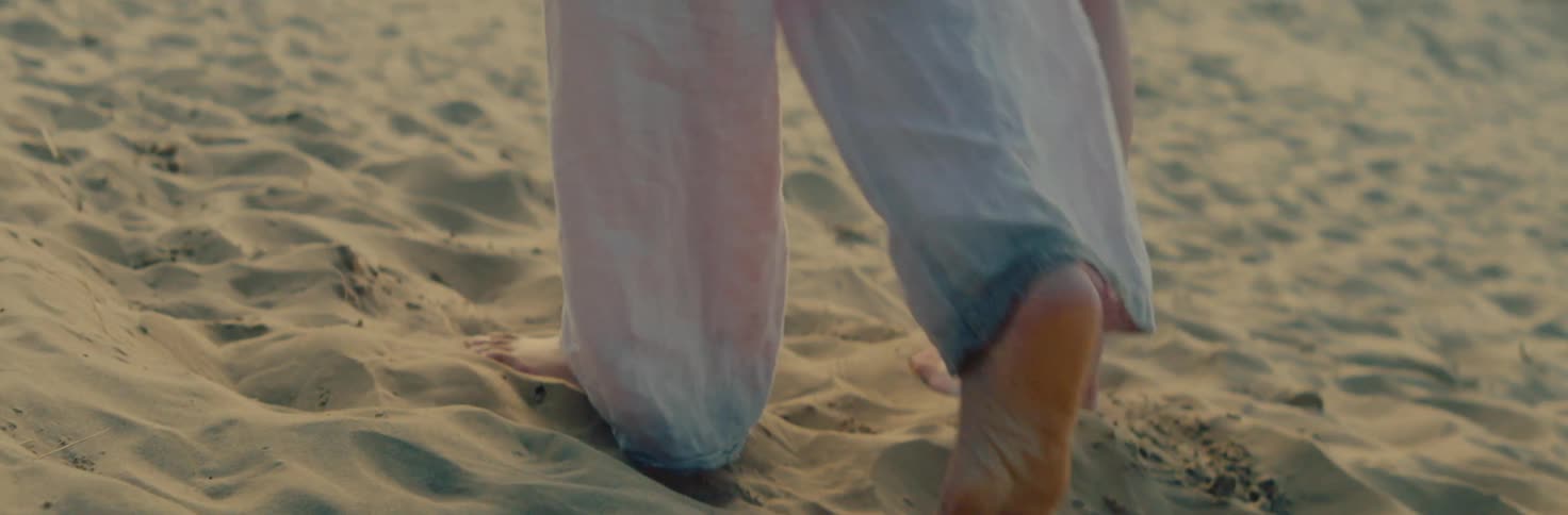 Close up of two women walking on the sand barefoot