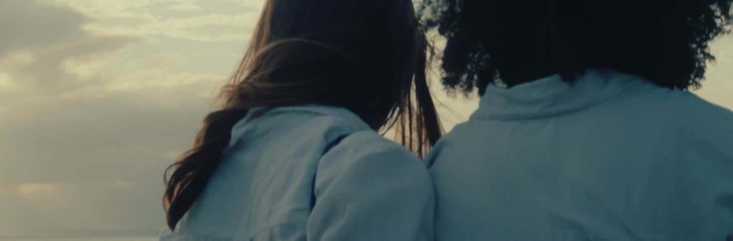 Couple leaning on a car watching the sunset over the ocean
