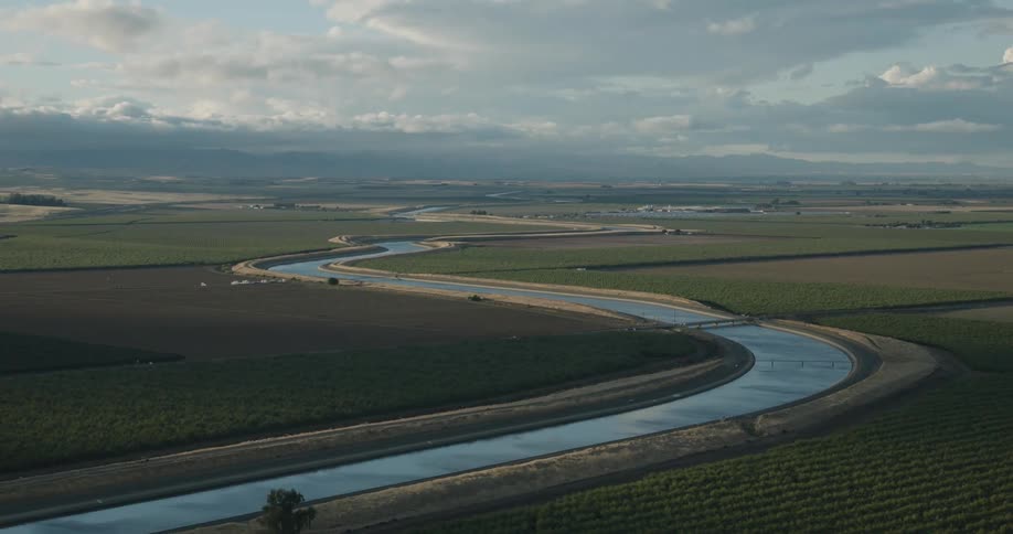Aerial view of a river in a canal surrounded by agricultural fields