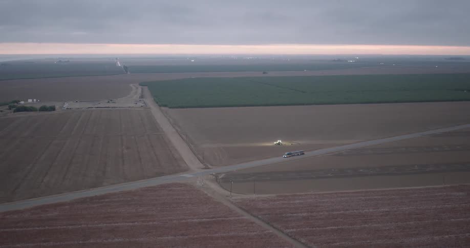 An aerial view of a rural landscape with a truck driving along a road between fields