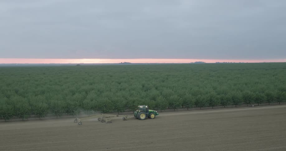 Aerial view of a tractor passing through an agricultural field in the morning