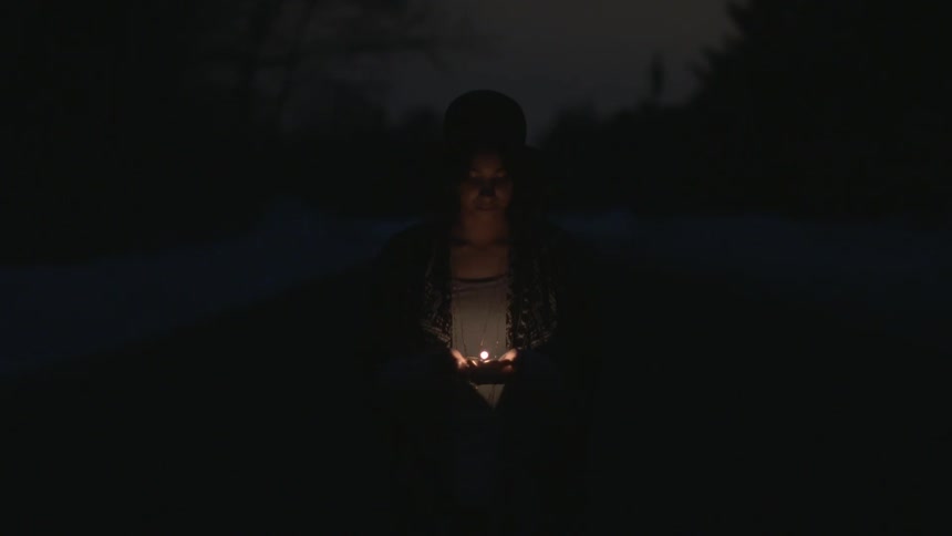 Woman holding a candle outside at night