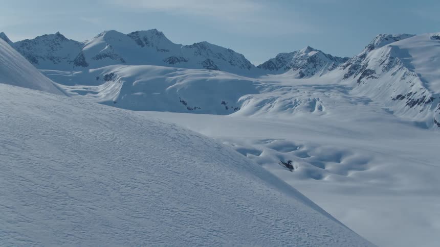 Person jumping from a snowmobile off a mountain