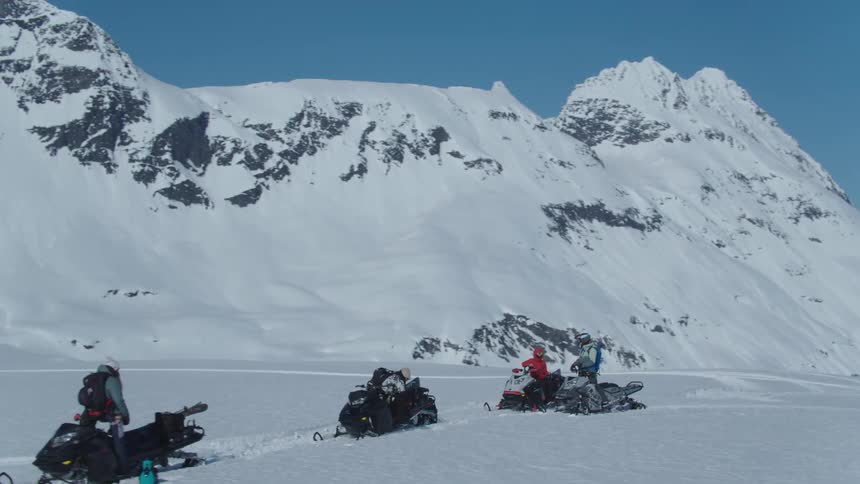 Four people on snowmobiles in mountains