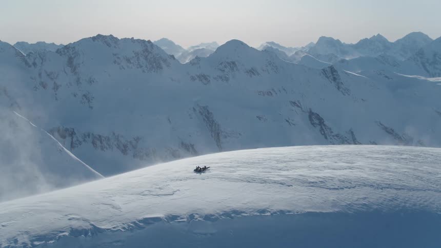 An aerial view of a group of people riding snowmobiles on a snowy slope