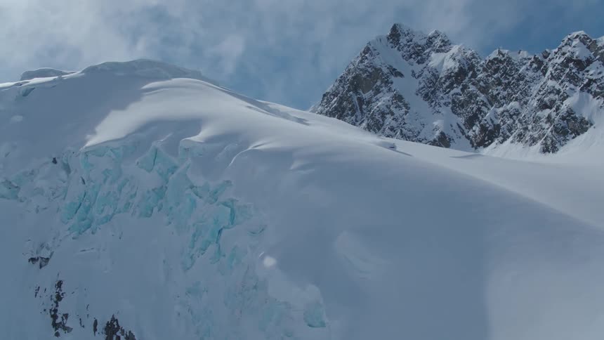 A person snowboards down a snow packed mountain