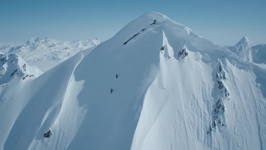 Aerial view of two people climbing snowy mountain cliff
