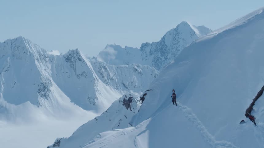 A person climbing the snow covered slopes of a mountain to reach the summit