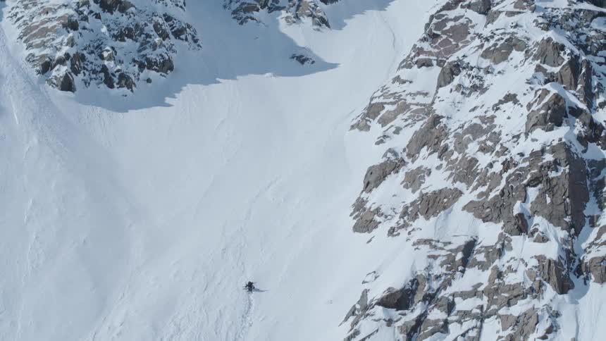 Person with ski equipment climbing a snowy mountain